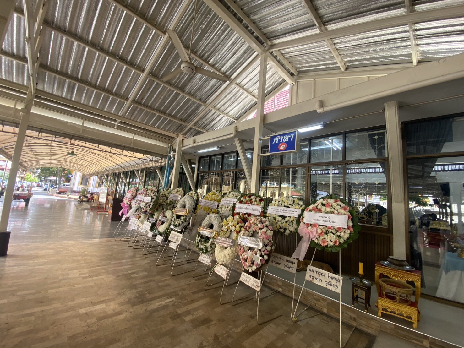 พวงหรีดหลากหลายแบบที่จัดส่งจริงเรียงหน้าศาลาวัดในปทุมธานี